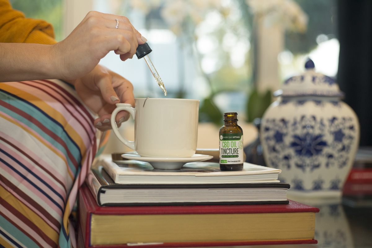 A seated person stirs Every Day Optimal CBD Oil into a cup of tea. When it comes to chronic pain, there's no clear winner in the CBD vs. THC debate: both have their uses.
